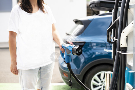 妇女收费电动汽车电源插座绿色生态概念图片
