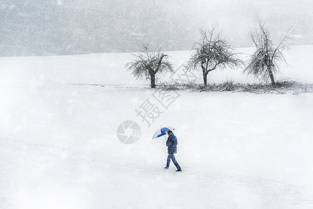 男子在寒冷的黄昏日在德国渡过严寒的冬季暴风雪天恶劣的气景象暴雪和狂风的一天背景图片