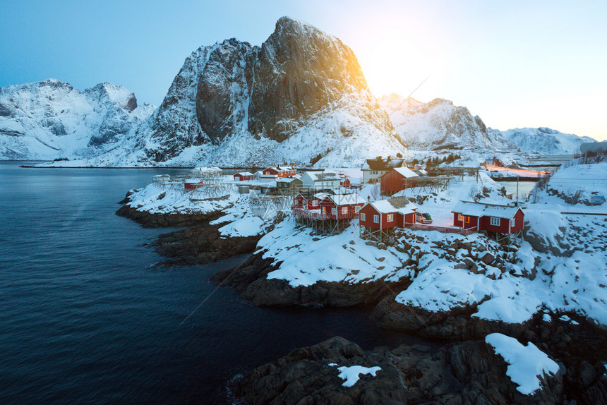 传统的挪威木制屋在峡湾的岸边和远处山上站立图片
