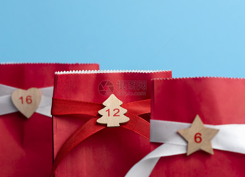 红色纸袋上面贴着丝带和蓝色背景的数字圣诞节进餐日历概念礼物时间xmas购物图片