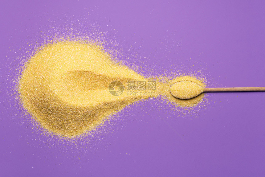 一大堆黄玉米面粉和满一勺的汤匙放在紫色背景上地玉米堆面包和饼的基本成分图片