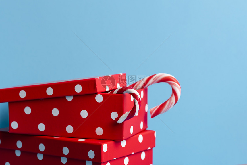 红色礼物盒上面有白色斑点和糖果甘蔗蓝色背景圣诞节礼物xmas红礼物概念冬季假日传统图片