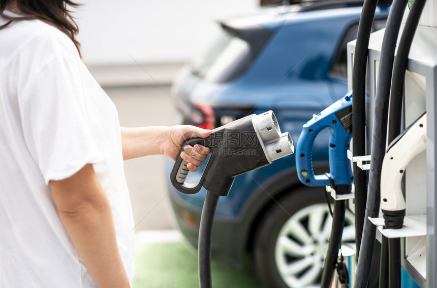 妇女收费电动汽车充电电源插座绿色生态概念图片
