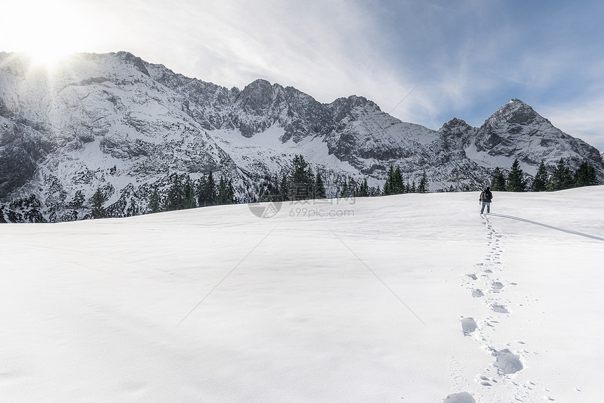 一个人独自走过雪向积高山靠近厄尔瓦德在奥斯特里亚阳光明媚的一天图片