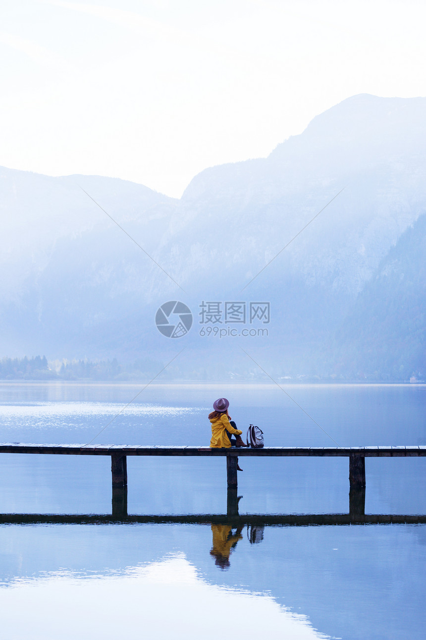 一大早带着背包坐在山湖上的木桥美丽的风景和反光图片