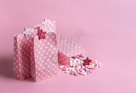 圣诞节进餐日历概念礼物袋装在粉红和白点上面有数字棉花糖果甘蔗圣诞传统框架背景图片
