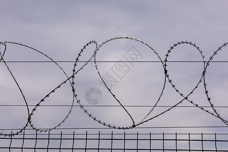 铁丝网从监狱栅栏上刺铁丝网被囚禁奴役犯被定罪监禁检查站安全区边境军事基地的概念背景图片