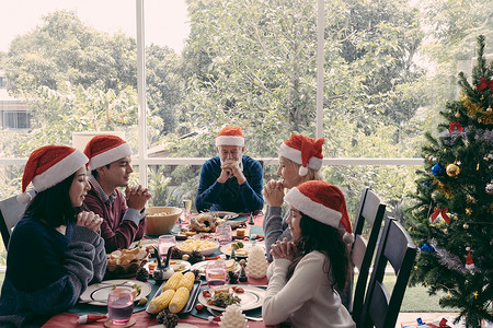 圣诞节一家人坐在餐桌前握手许愿装饰高清图片素材