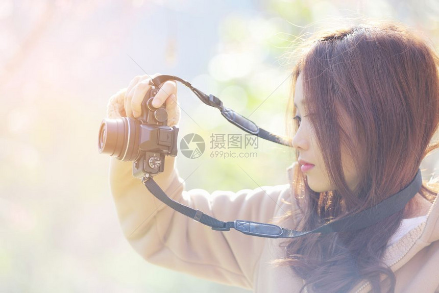 美丽的年轻女子拍照与开花樱萨库拉图片