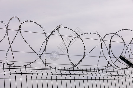 铁丝网从监狱栅栏上刺铁丝网被囚禁奴役犯被定罪监禁检查站安全区边境军事基地的概念背景图片