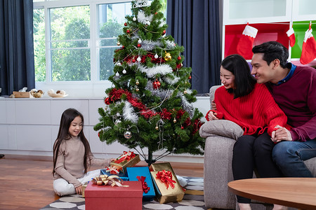 亚足幸福的家庭父亲母女儿帮助准备和赠送或装饰在客厅的圣诞树或装饰图片