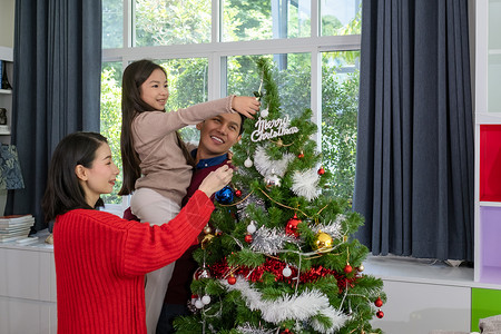 儿家庭亚足幸福的家庭父亲母女儿帮助准备和赠送或装饰在客厅的圣诞树或装饰背景