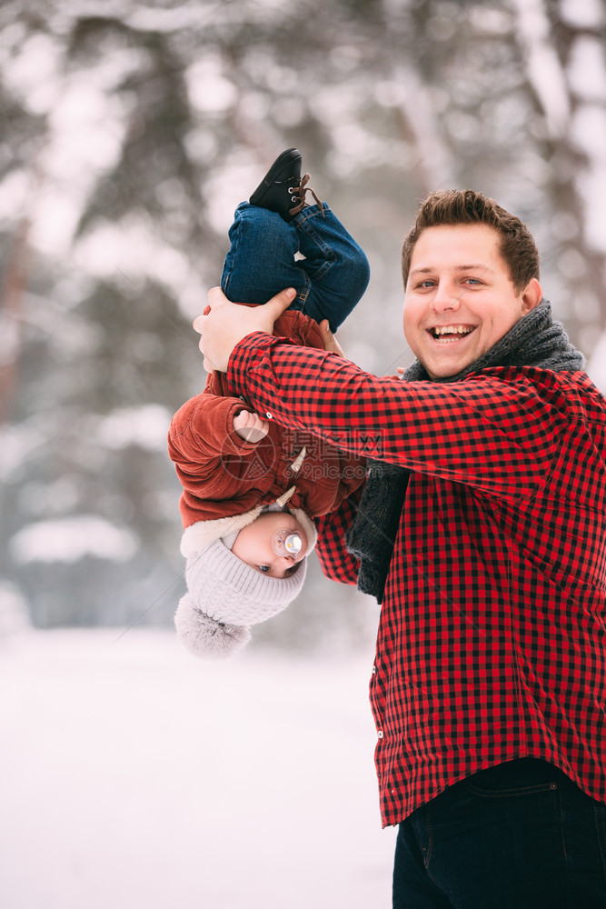 快乐的爸和小儿子在冬季雪林里玩乐的肖像图片