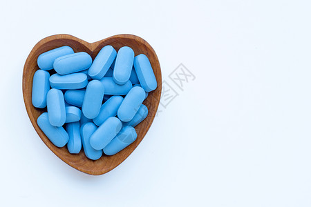 具有心脏形状的蓝医用药丸白色背景的木碗复制空间高清图片