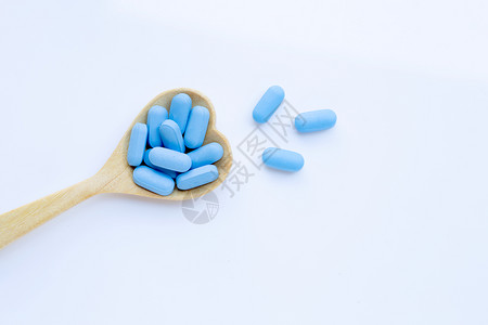 蓝色木具有心脏形状的蓝医用药丸白色背景的木勺复制空间背景