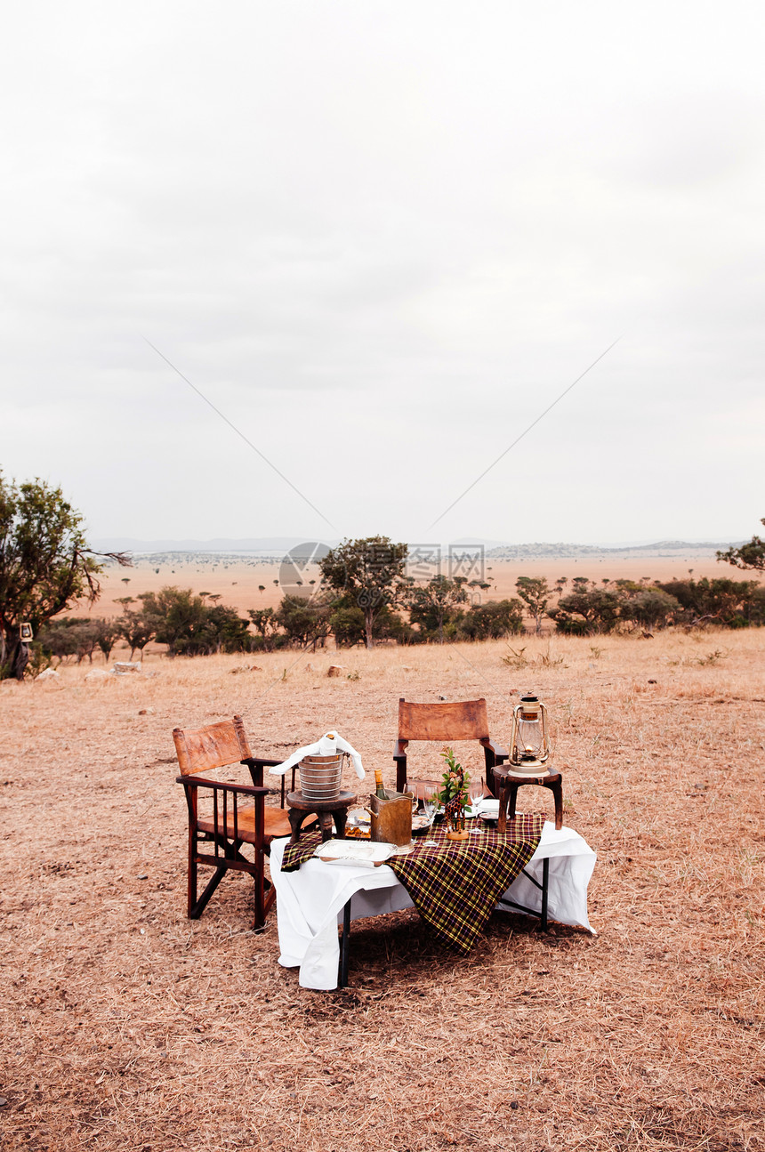 野外餐非洲风格的木制导演椅子桌上摆着酒桶SanegtiSanv森林的非洲户外餐厅图片