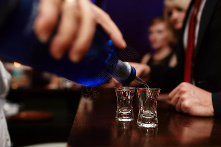 小吧黎酒吧酒吧保将烈精饮料倒在吧的小杯子中在夜总会或酒吧中声背景