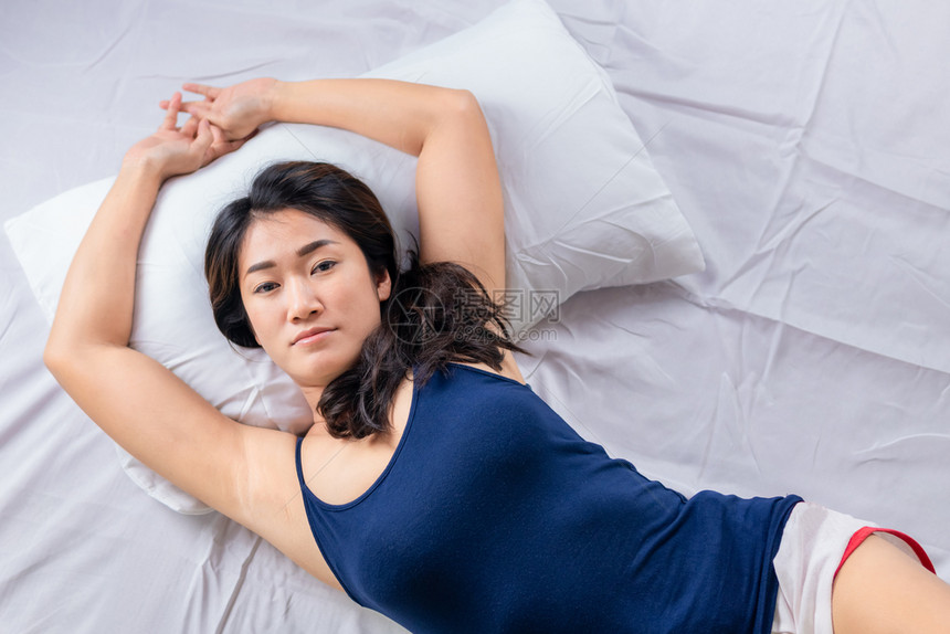 一位年轻迷人的亚洲女早上躺在床时伸出双手图片