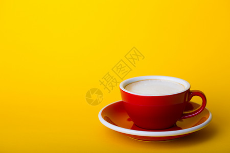 黄底带卡布奇诺的美丽咖啡红杯背景图片