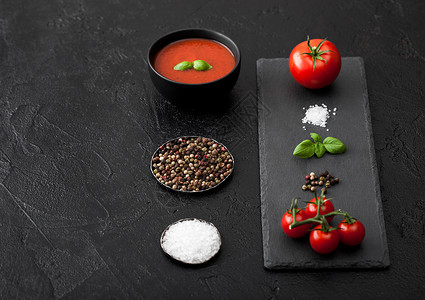 黑碗底番茄奶油汤用石头切面板和生西红柿胡椒和盐图片