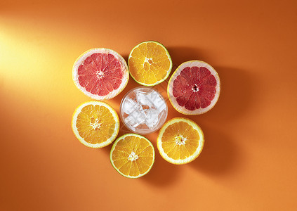 橙色冰块素材夏季鸡尾酒成分含柑橘水果和玻璃在阳光下橙色底面有冰块新鲜橙子和葡萄果切成两半背景