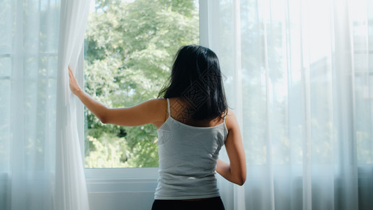 年轻女孩拉开窗帘背景图片