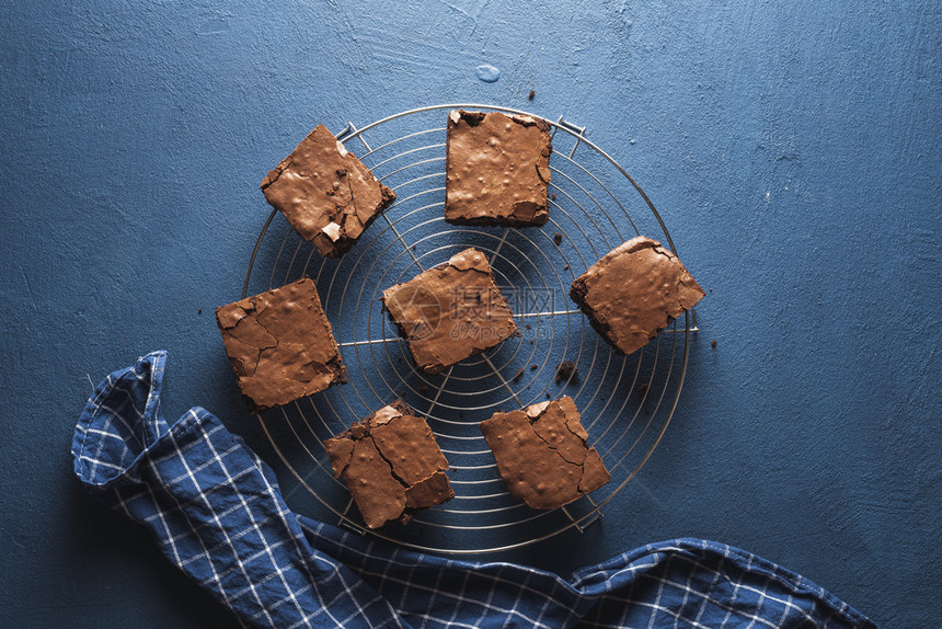 在冷却架上经典的蓝桌和厨房毛巾上最美味的巧克力甜点蛋糕方形图片