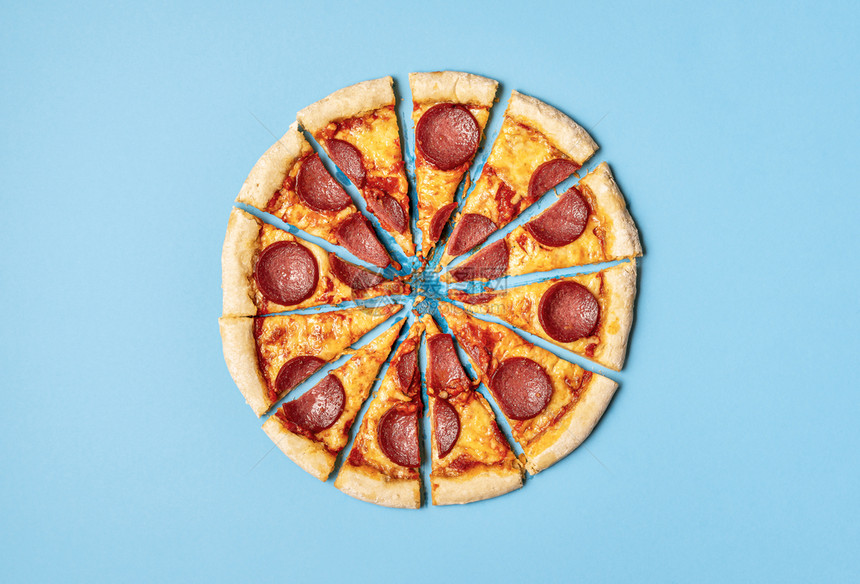 在一片蓝色背景上被隔离的切片开比萨拉米在切片的披萨辣椒上将分成部著名的食物油腻盘子图片