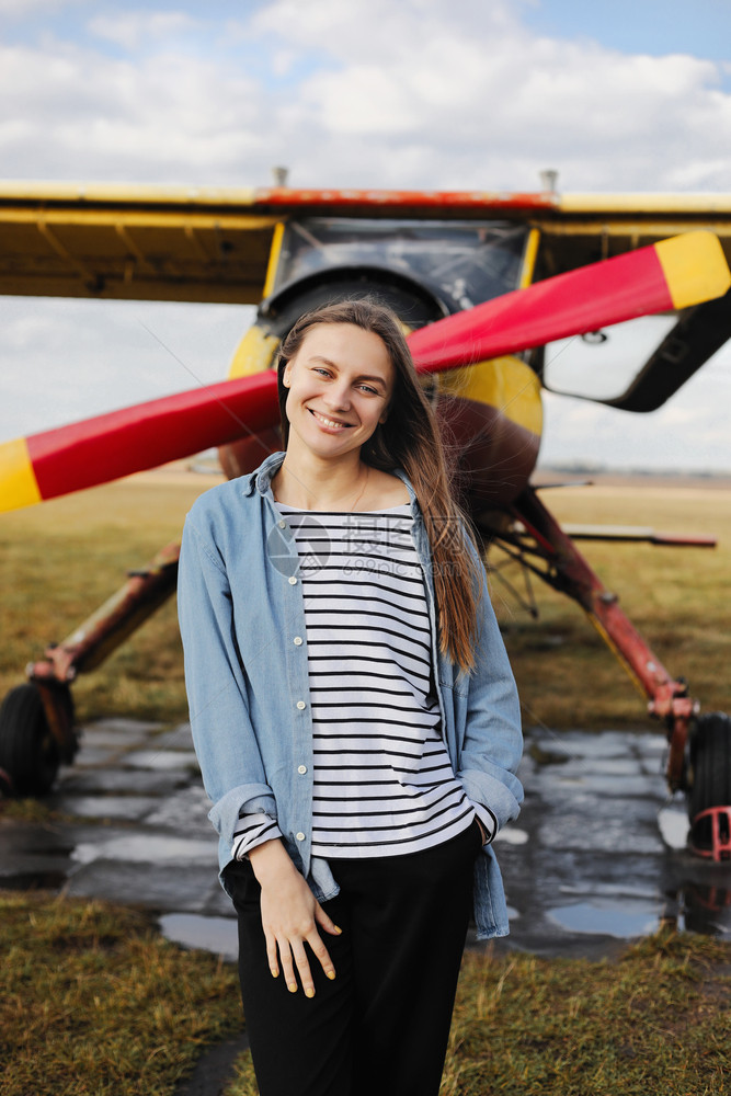 女青年站在飞机的旁边摆姿势图片