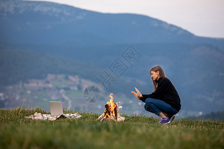 女青年坐在火边暖手女图片