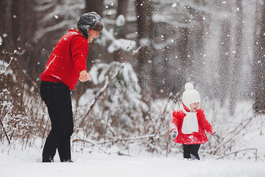 快乐的小女孩穿着红色大衣父亲在冬季森林里玩雪女孩和爸一起玩在冬天森林里玩雪图片