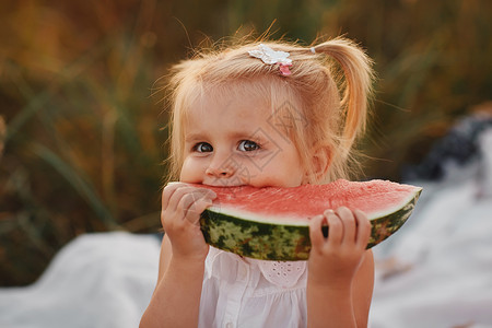 令人难以置信的美丽红头发小女孩吃了西瓜健康的水果零食可爱的小孩卷发蹒跚学步的孩子高清图片素材