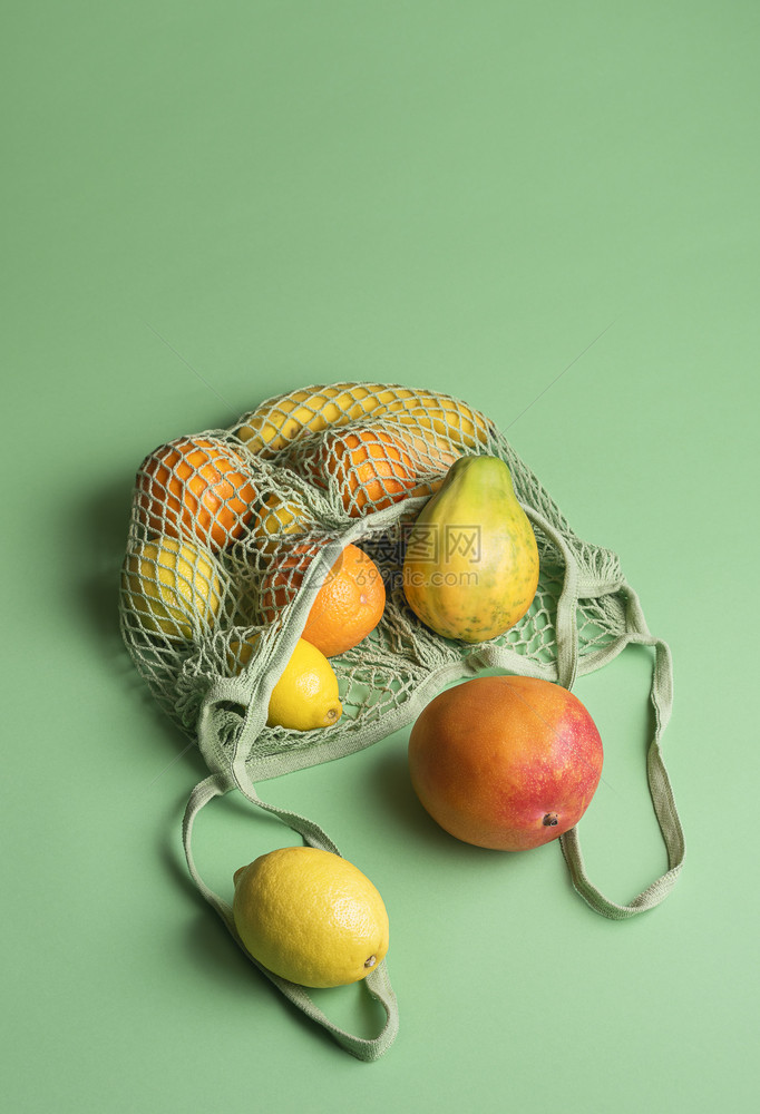 有机热带水果混杂在绿色背景的织物网状购袋中食品概念夏季异国水果零售环境图片