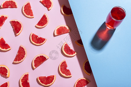 蓝色背景的葡萄汁柠檬杯和粉红色背景的葡萄汁片图片
