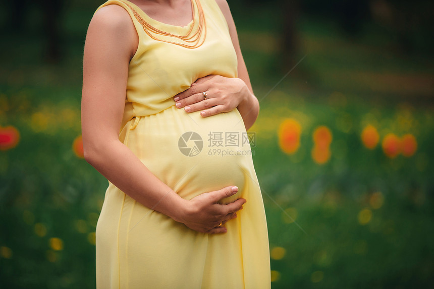 身穿黄裙子的怀孕女孩在田里抱着肚子图片