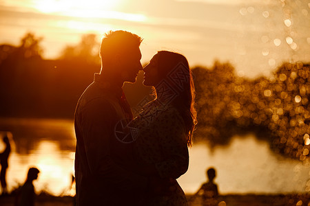年轻夫妇在落日的湖边接吻图片