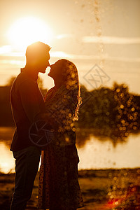 年轻夫妇在落日的湖边接吻图片