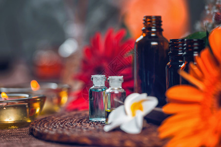 含蓝色和绿基本油多彩红花和橙色朵及蜡烛的透明芳香治疗瓶的法成分自然的高清图片素材