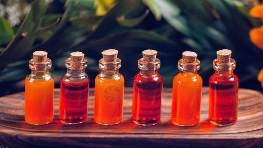 木板上装满红和橙色基本油的透明瓶子自然的高清图片素材