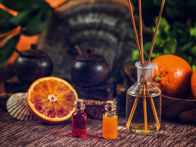 装满红色和橙基本油芳香药瓶的子里面有木棍新鲜柑橘水果被切成两半护肤品高清图片素材