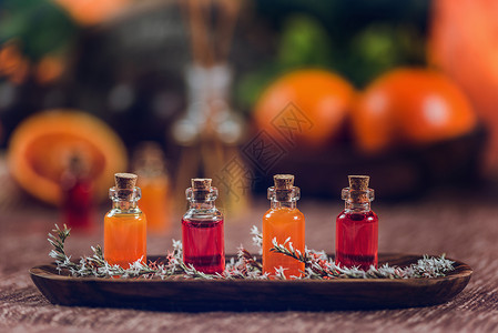 木板上装满红和橙色基本油的瓶子新鲜柑橘水果切成两半棍枝高清图片素材