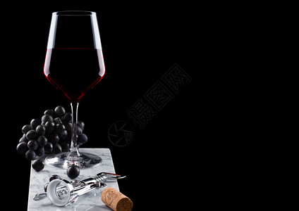 张裕解百纳玻璃红葡萄酒大理石板上有深葡萄软木瓶开器和黑底的软木瓶背景