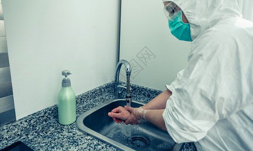 在细菌防护西装中无法辨认的妇女用肥皂洗手高清图片
