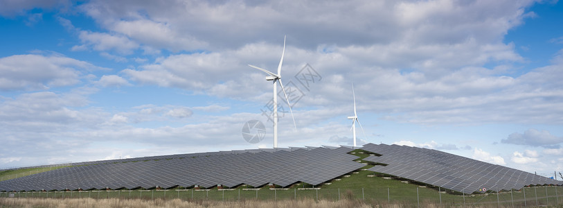 风涡轮机和太阳能电池板形成在蓝色天空下有云层的内河地带替代诱导植物背景图片