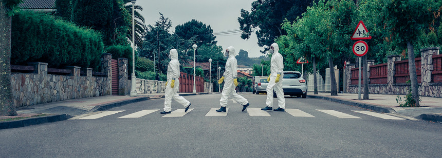 身着细菌保护西装的人群在一条空街上穿越横行图片