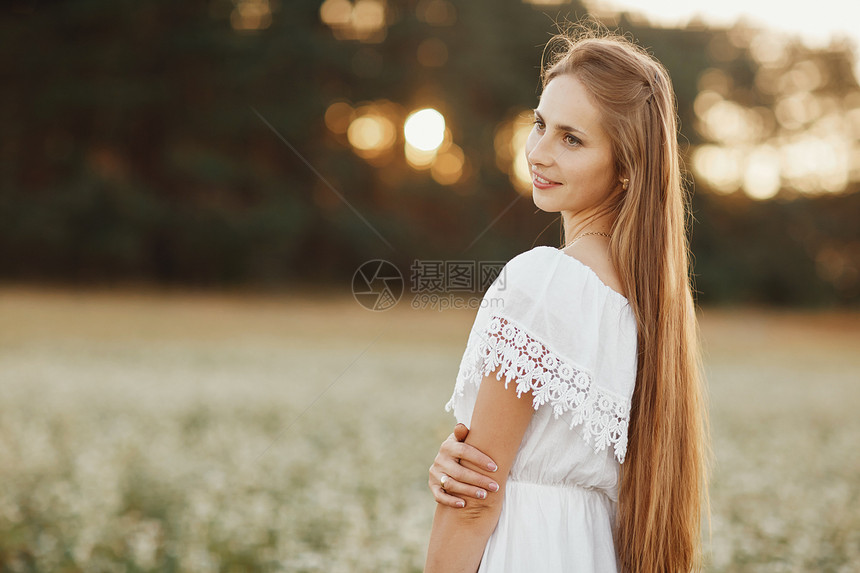 一个美丽的女孩肖像穿着白色的礼服在开花田野里一位美丽的女孩肖像在开花田里朵野夏天与自然的团结图片