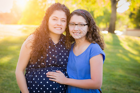 患有西班牙血统的怀孕母亲与年轻女儿一起户外活动图片