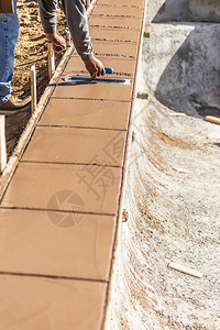 建筑工人在新的游泳池周围利用湿水泥的粗糙土来应对背景图片