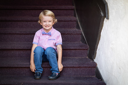 坐在楼梯阶上可爱的男孩肖像家庭高清图片素材