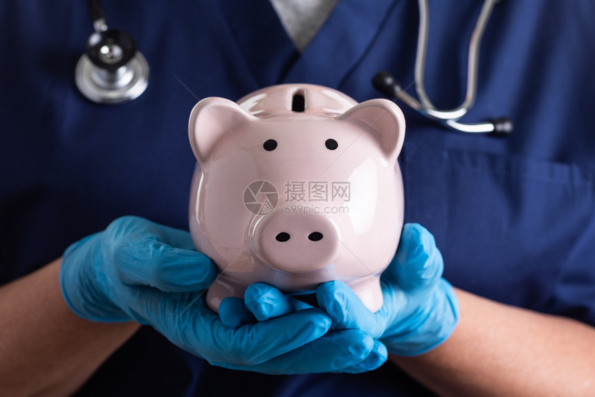 医生或护士佩戴手持小猪银行的外科手套图片
